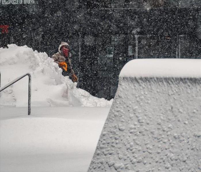 A man shovels snow in front of a business