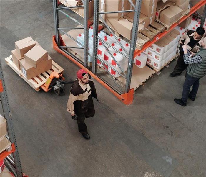 Workers in a warehouse with shelves and boxes