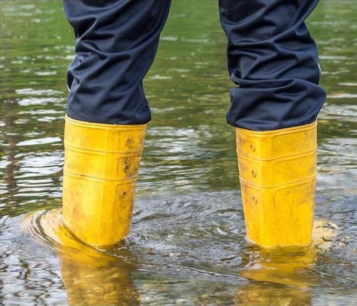 Man in yellow boots standing in flood